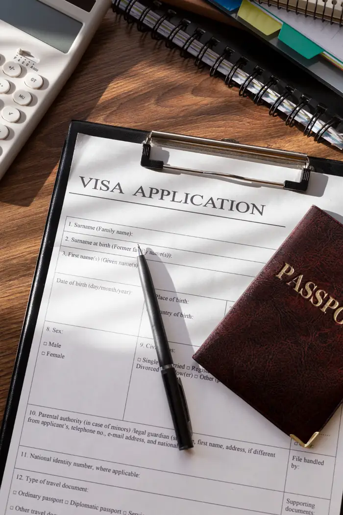 A visa application on a clipboard beside a passport and pen