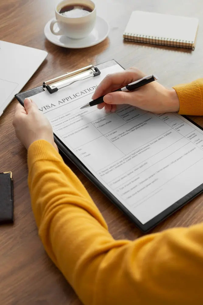 A person filling out a visa application on a clipboard