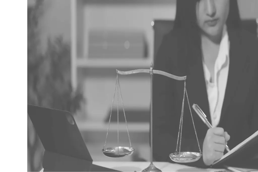 A woman at a desk with a brass scale of justice